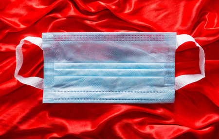 Blue medical mask on red silk fabric
