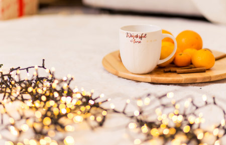 A white cup with the inscription Wonderful Winter stands on a wooden tray, pallesins and cinnamon lie next to it. The tray is on a soft white carpet. Horizontal photoの写真素材
