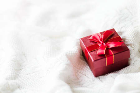 Christmas card with gift box red ribbon on white knitted sweater background. Copyspace. Horizontal photoの写真素材