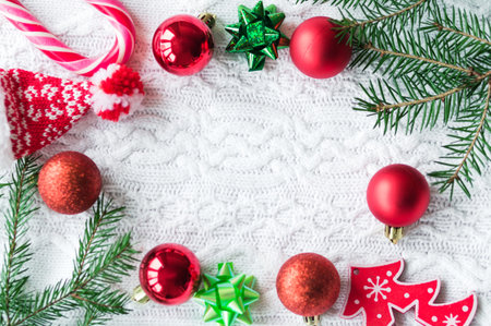New year frame mockup. Pine cones, fir branches and Christmas balls on white knit background. Flat...