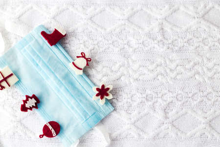 Medical mask with christmas pins on white knitted background. Horizontal photoの写真素材
