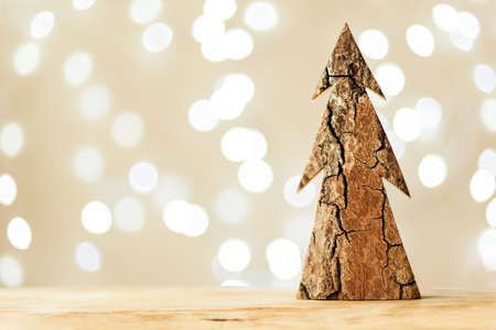 Handmade wooden Christmas tree stands on a wooden tray on a light color background with bokeh. Horizontal photoの写真素材