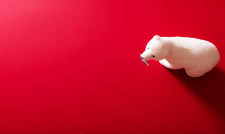 Toy polar bear with fish in mouth on red background. Horizontal photoの写真素材