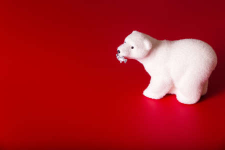 Toy polar bear with fish in mouth on red background. Horizontal photoの写真素材