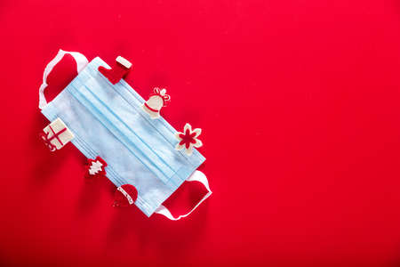 Medical protective mask with decorative wooden clothespins on a red background. Protection from coronavirus. Horizontal photoの写真素材
