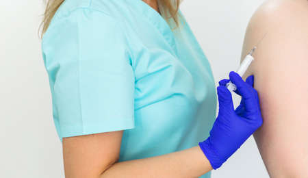 close up doctor holding syringe a before make injection to patient in medical mask. vaccineの写真素材