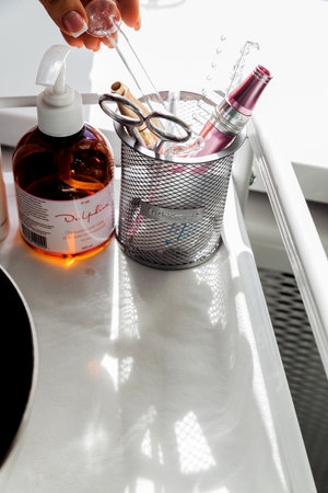 Minsk -Belarus, 5 march 2021.Cosmetics and appliances on the beauticians desktop. Sunlight falls from the windowのeditorial素材