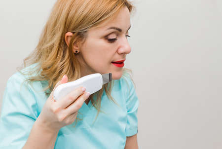 The doctor consults, teaches and shows how to do an ultrasound of the face with a special device. Horizontal photoの写真素材