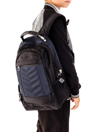 A schoolboy with a black bag on his shoulder stands on a white background in a school uniform -...