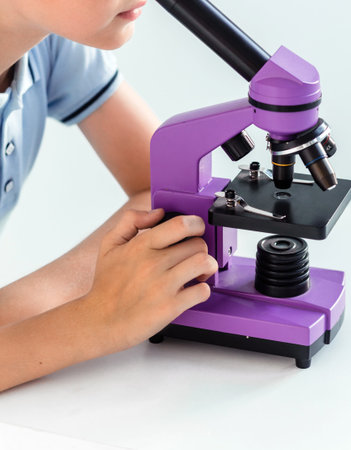 Boy in blue polo looks through a purple microscope
