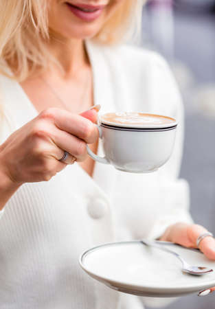 Girl in jeans, pink hoodie and black jacket posing on a city street. Photoの写真素材