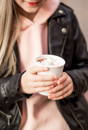 Girl in jeans, pink hoodie and black jacket posing on a city street. Photoの写真素材
