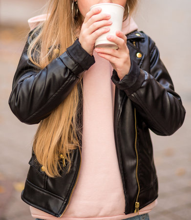 Girl in jeans, pink hoodie and black jacket posing on a city street. Photo