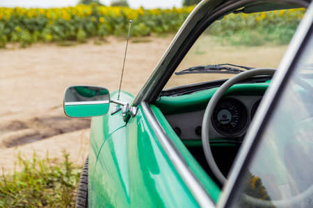Classic car chrome mirror. Volksvagen Karmann Ghia Coupe, green retro car on sunflower field. Italian classic car - Minsk, Belarus - July 10, 2021のeditorial素材