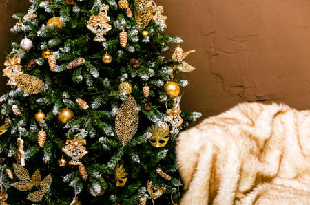 A sofa with a fur cape and a Christmas tree with gifts in a stylish home interior. New Year decor. Photoの写真素材