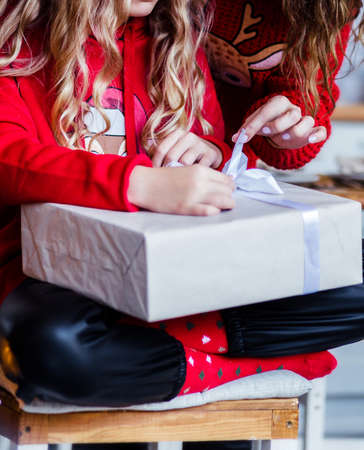 mom and daughter in red sweaters open a New Year's gift. Photoの写真素材