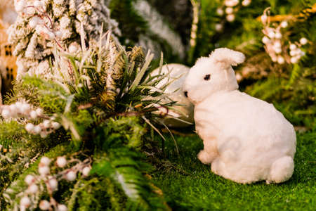 Toy white rabbit sits on artificial grass in New Year decor. Photoの写真素材