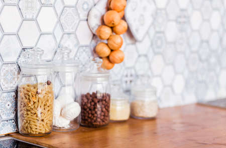On the kitchen table, there are jars with various products - pasta, marshmallows, nuts. Photoの写真素材