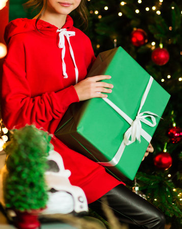 A girl in a red bike sits and holds a gift in green wrapping paper in her hands. Photo