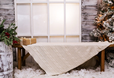 Photo studio decor. The bench stands in front of the window of a wooden house, a white plaid lies on...