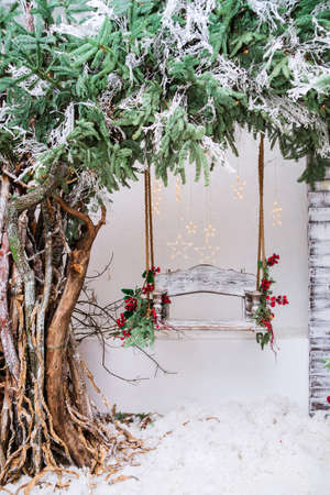 Wooden swing in a snow-covered park or forest with spruce tree and while snowing, Christmas and New Year holiday concept. Photoの写真素材