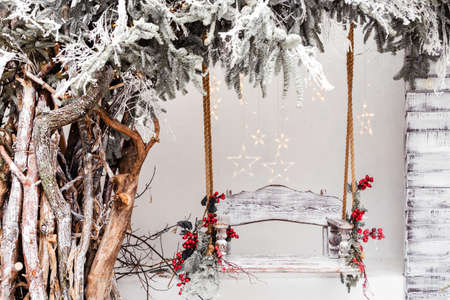 Wooden swing in a snow-covered park or forest with spruce tree and while snowing, Christmas and New Year holiday concept. Photoの写真素材