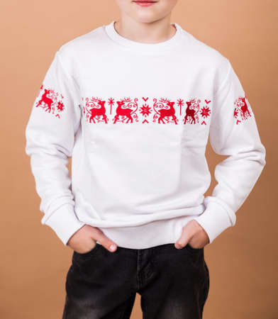 Boy posing in white pullover with red print on beige backgroundの写真素材