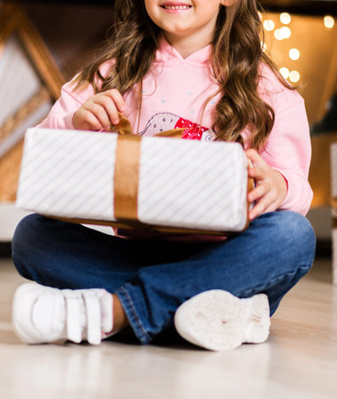 Girl in a pink sweater and jeans posing with a New Year's gift in her handsの写真素材