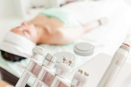 The girl patient lies in the cosmetologist's office on the couch next to the cosmetic machine. The girl is waiting for the procedure to beginの写真素材