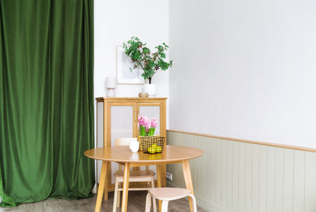 The interior of the kitchen is made of natural materials. There are plants, a table and a green...