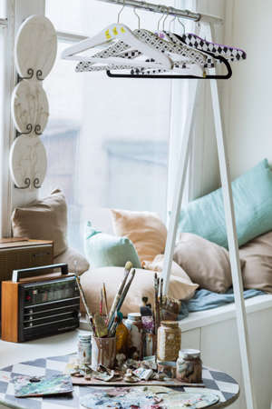 Paint brushes and oil paints on the table in front of the window. Hobby and informational detox conceptの写真素材