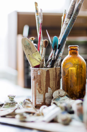 Used paint brushes and oil paints in tubes are on the table. Fine art set