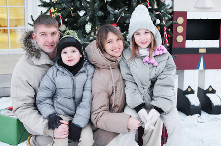 A family of four poses in the yard of their house in winter