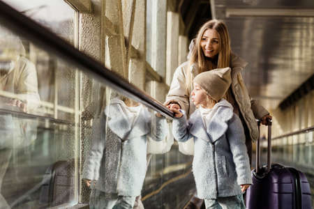 Mom and daughter go up the escalator to the building of the stationの写真素材