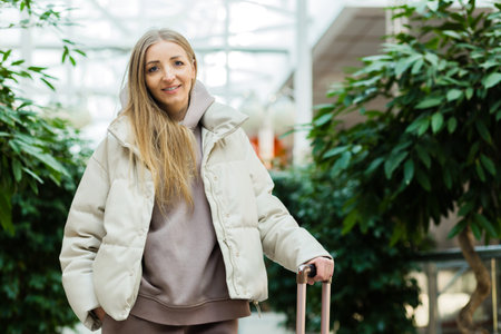 woman with luggage in Airport waiting room looking at camera.