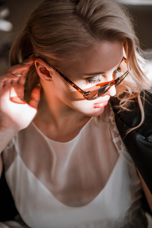 Beautiful blonde young bride woman in white wedding dress, black leather jacket and sunglasses.
