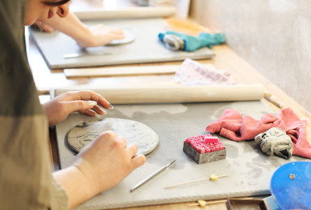 A potter makes an inscription or drawing on a wet clay plate. Concept of manual labor or small...