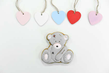 Gingerbread in the shape of a gray teddy bear on a white background decorated with colorful hearts. Top viewの写真素材