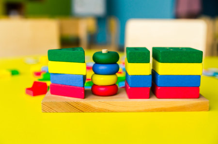 Colorful wooden blocks on yellow table. Creativity toys. Children building blocks. Geometric shapes - circle, triangle, square, rectangle. The concept of logical thinking. Horizontal photoの写真素材