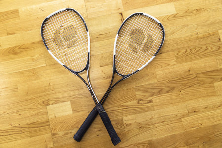 Two old squash rackets lie on a parquet background. Top view. Minsk, Belarus- May 25, 2022