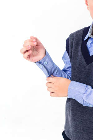 The boy poses in a school uniform on a white background. The model shows the sleeves of the shirt, the quality of the tailoring and the material. Vertical photoの写真素材