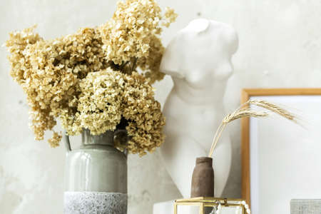Interior greek statue of a woman on the background of a white wall . Beautiful vase  with dry flowers in a vase,  minimalistic modern interior. Horizontal photoの写真素材