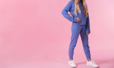 A teenage girl demonstrates a blue tracksuit on a blue background. Horizontal photoの写真素材