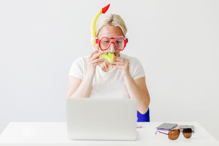 Woman in diving mask seeking offers on-line for your vacation on the beach. Woman dreaming of sea at workplaceの写真素材