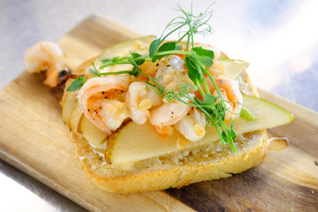 Bruschetta with shrimp, pear and pine nuts on a wooden board. Horizontal photoの写真素材