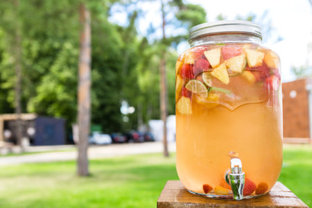 Refreshing lemonade with lime, strawberry and pineapple in glass jars with tap. Concept of drinks,...