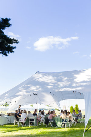 Summer party on a green lawn under a white tent. Horizontal photo. Minsk, Belarus - August 15, 2022の写真素材