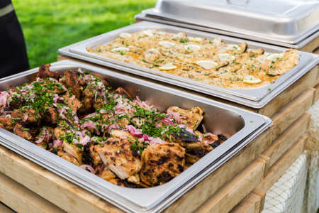 In a metal steamer BBQ pork with onions. Summer picnic. Catering job. Horizontal photoの写真素材
