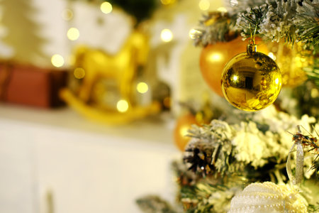 Evening Christmas atmosphere. Christmas balls of golden color hang on the Christmas tree. Horizontal photoの写真素材