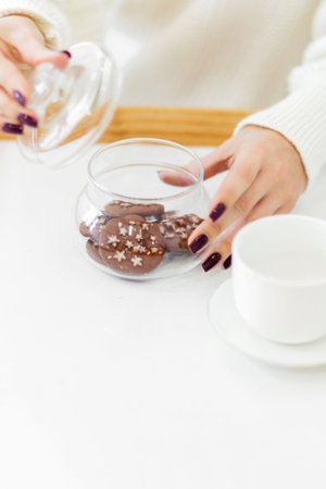Female hands open a glass jar with Christmas cookies. Vertical photo